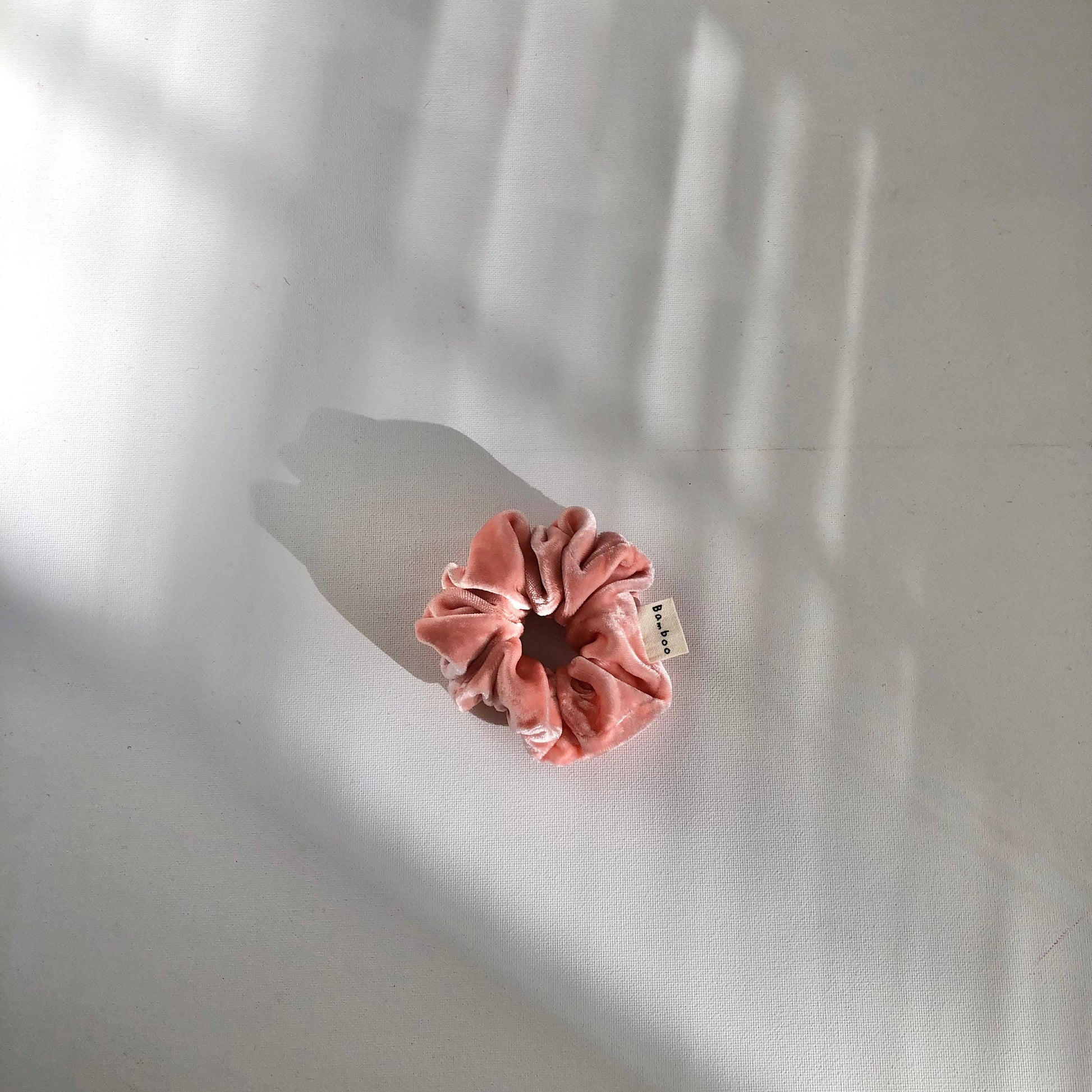 Pink scrunchie with a tag on a white background