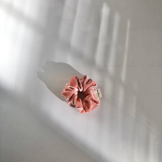 Pink scrunchie with a tag on a white background